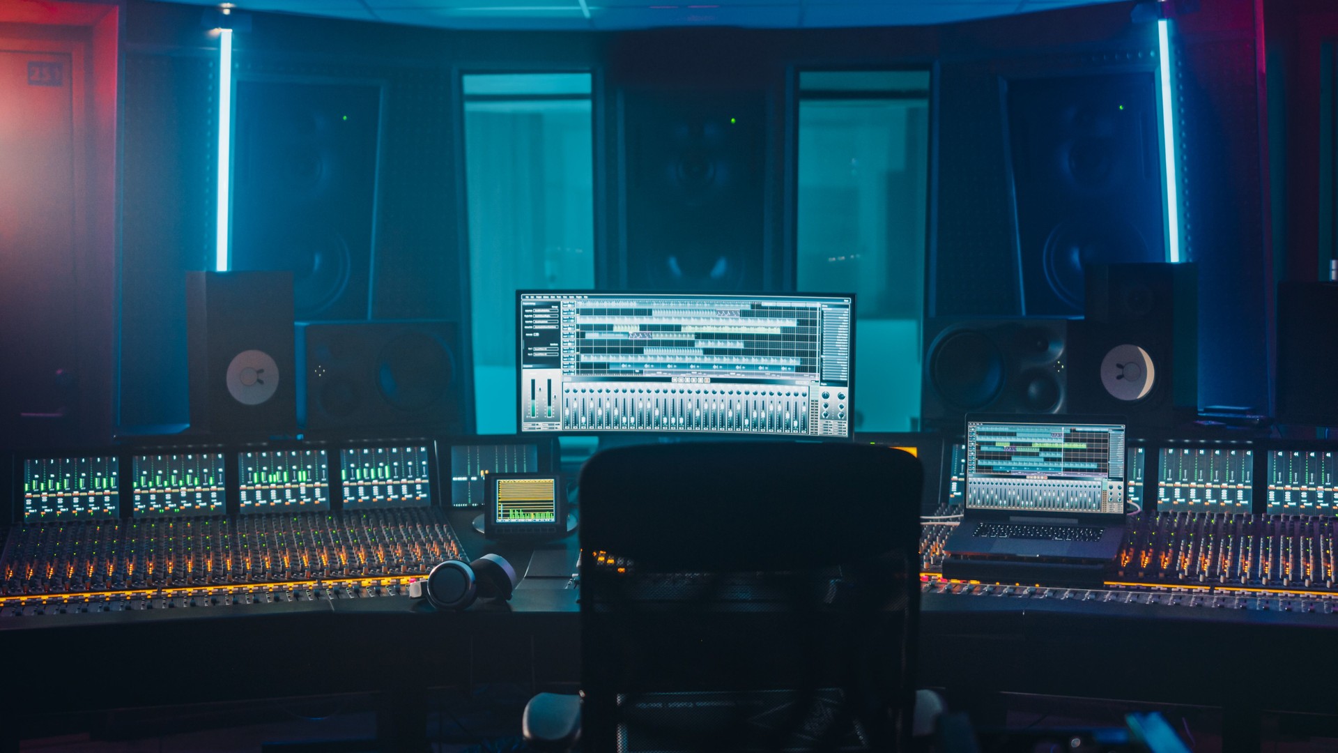 Shot of a Modern Music Record Studio Control Desk with Computer Screen show User Interface of DAW Software with Song Playing. Equalizer, Mixer and other Professional Equipment.